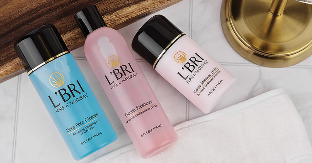 Deep Pore Cleanser (blue) Gentle Freshener (pink) and Gentle Moisture Lotion (pale pink) laying on a bathroom counter next to a gold mirror base